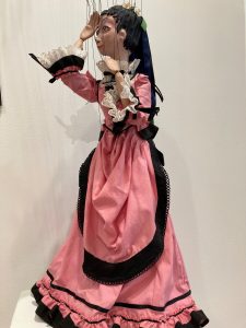A marionette puppet of a woman in a pink Victorian dress.