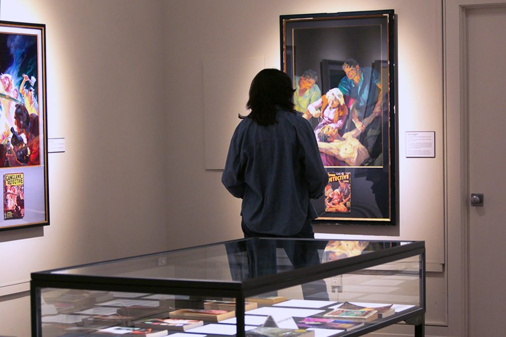 A student in an art gallery admires a painting of a pulp novel cover