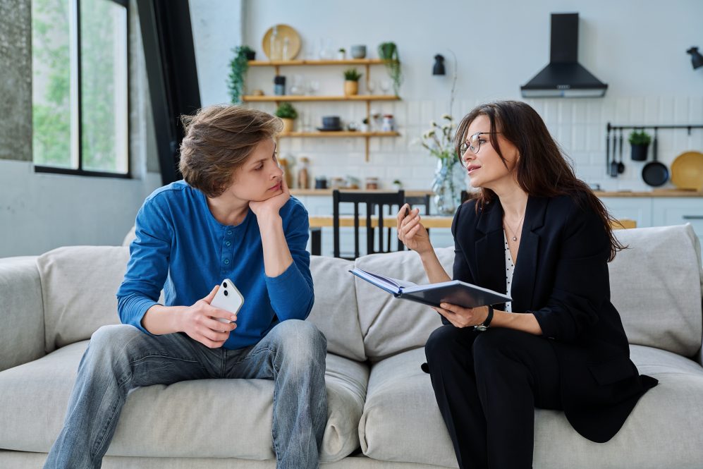 Female social worker mental health specialist working with teenage guy, home visit, survey consultation. Psychological social services, psychology psychotherapy counseling help treatment support