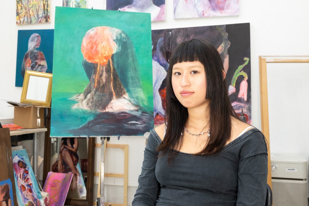 A student posing in front of painted canvases