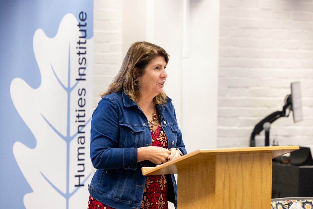 A professor smiling and giving a speech at a podium