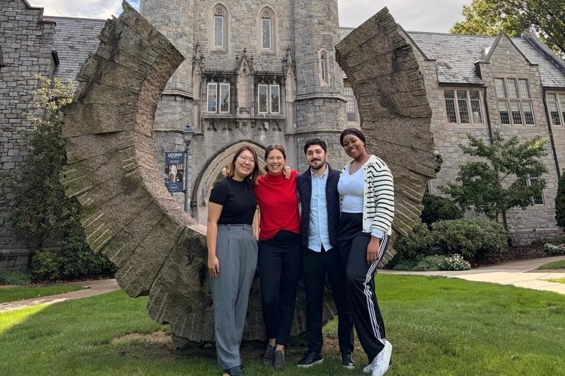 The four Fulbright scholars pose in front of the Middle Path sculpture