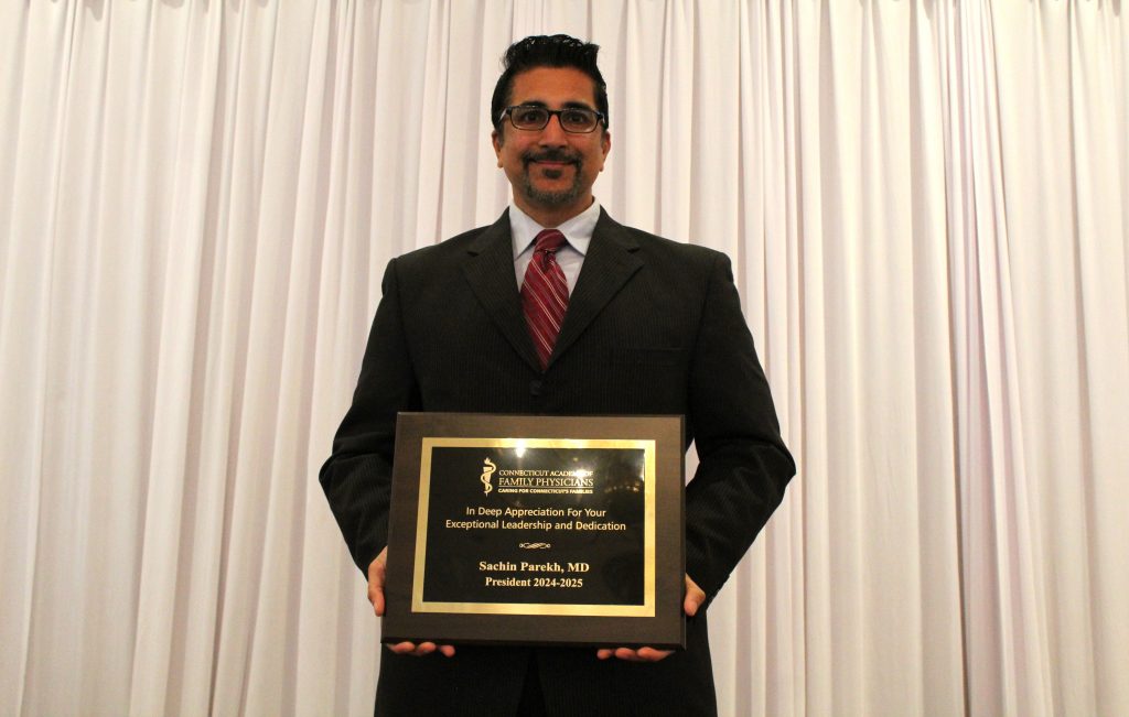 UConn SOM alum Dr. Sachin Parekh, holding an award.