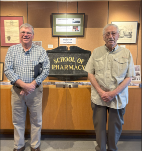 two men standing in front of library artifact display case