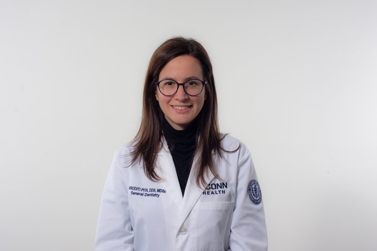 woman in white coat and glasses in front of white background
