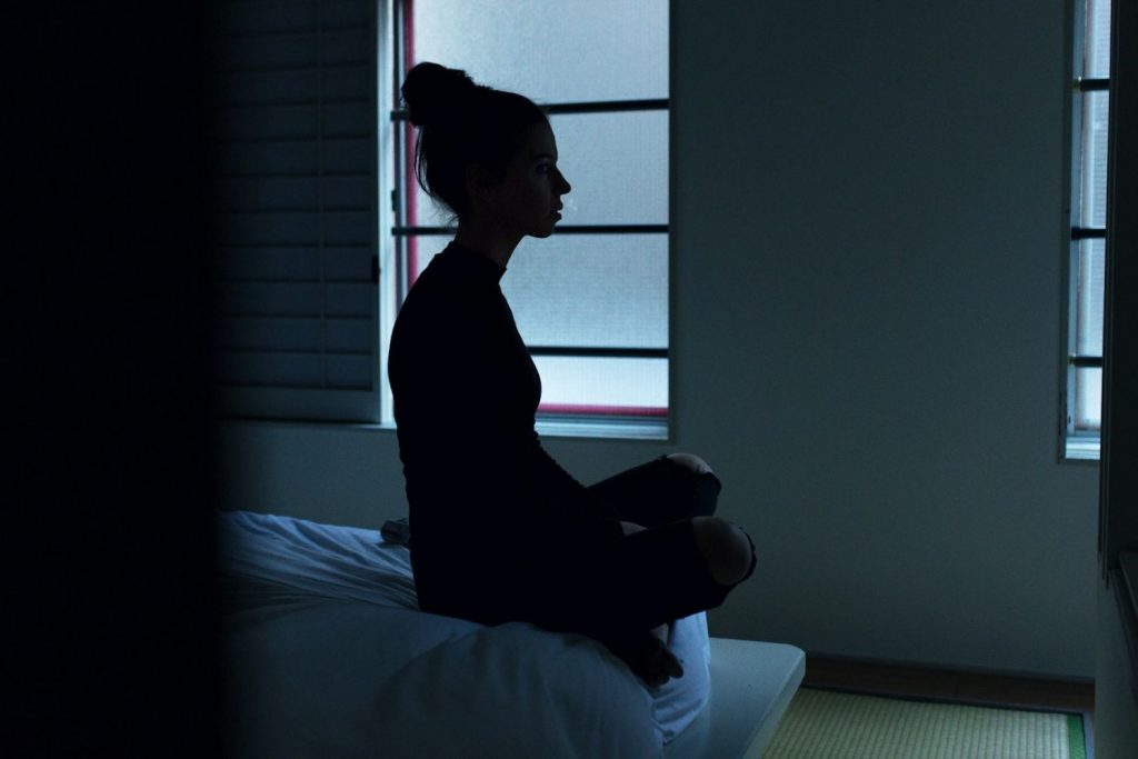 Woman sitting on a bed in the dim light