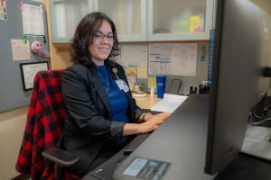 Mirsa Claudio is the administrative program assistant for the Blood and Marrow Transplantation typing on a computer at her desk 