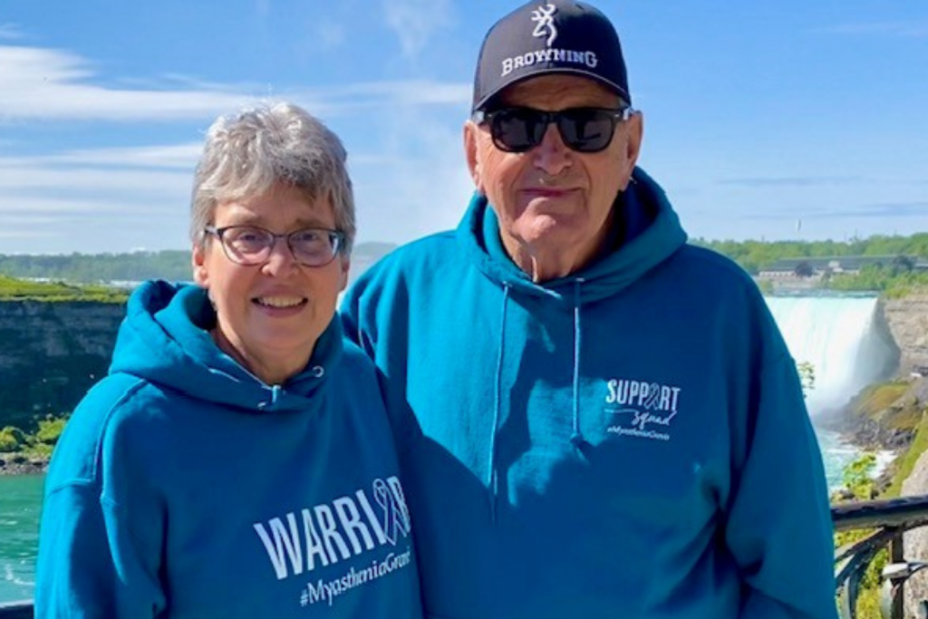 Woman and man in teal sweatshirts posing in from of Niagara falls