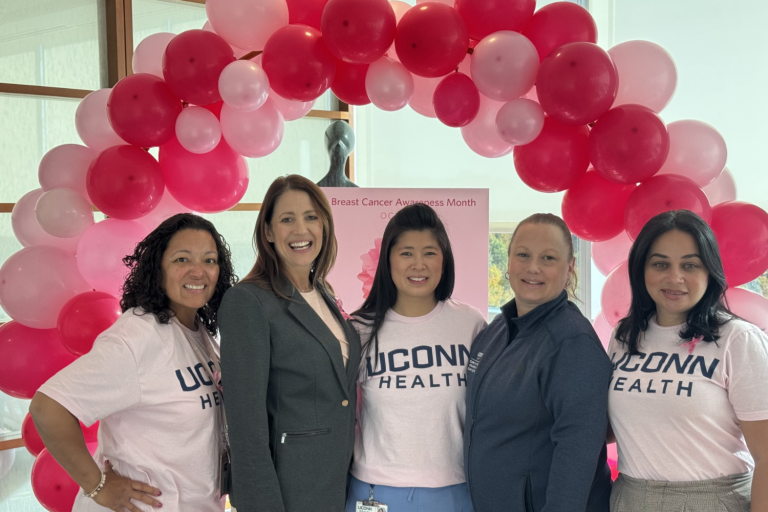 5 women stand in front of a pink balloon arch