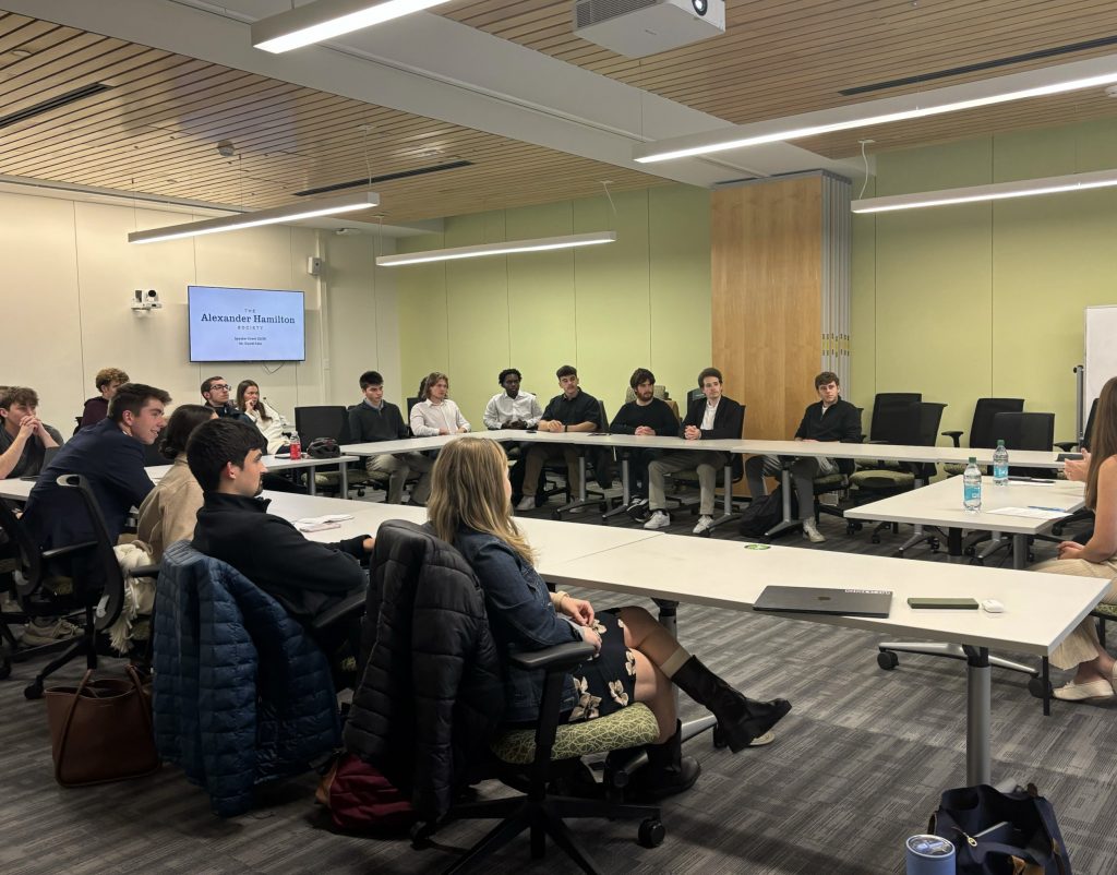 A group of young adults in a conference room listening to a presenter.