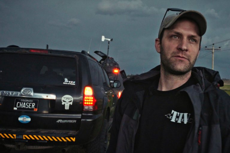 A man stands in front of an SUV.