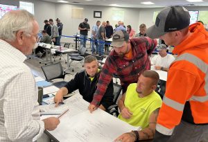 Participants in a classroom collaborate on construction plans during a training session.