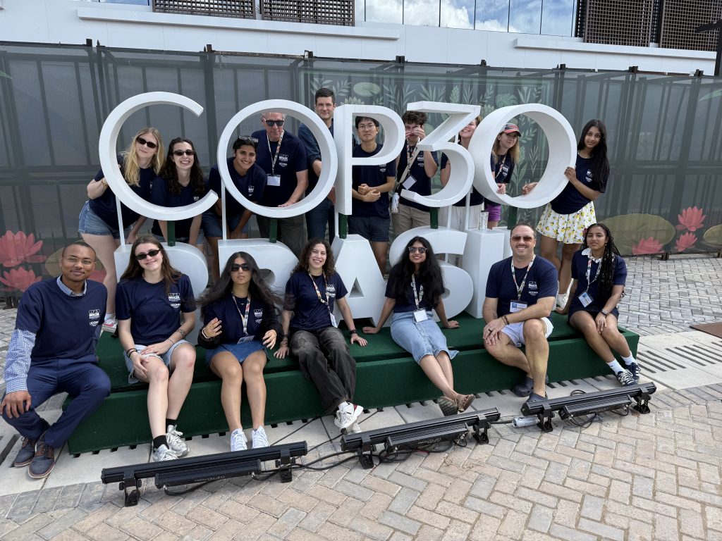 UConn students standing in front of a "COP30" sign