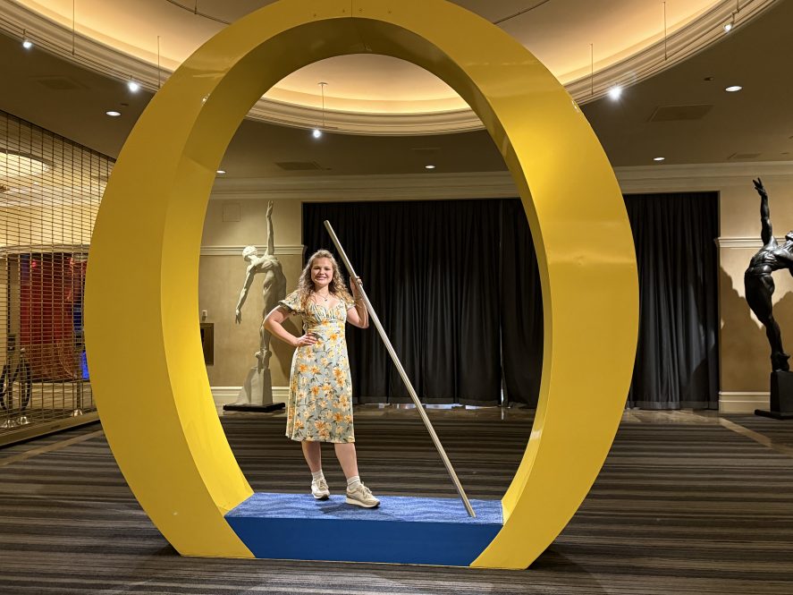 A young woman stands inside a large sculpture in the shape of the letter O.