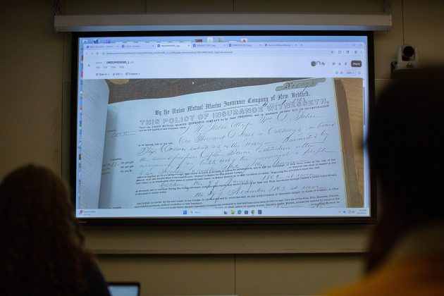 An 1860s insurance policy from the from the Union Mutual Marine Insurance Company of New Bedford is projected to students in Remy Levin's Historic Risk Lab.