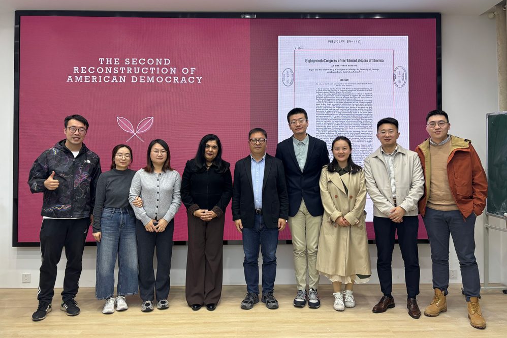 Nine people stand in front of presentation.