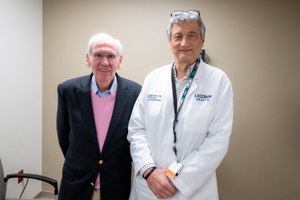 Grateful patient Woody Exley with his longtime physician Dr. Mark Metersky in exam room smiling.