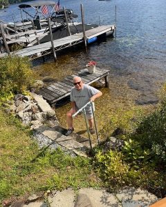 Man walking up steps and holding handrail by the edge of a lake