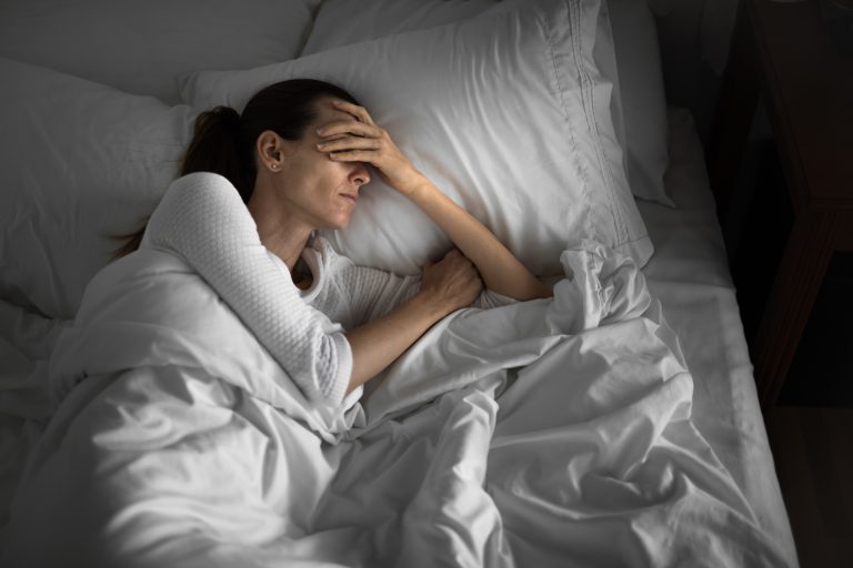 A woman in bed showing signs of poor sleep