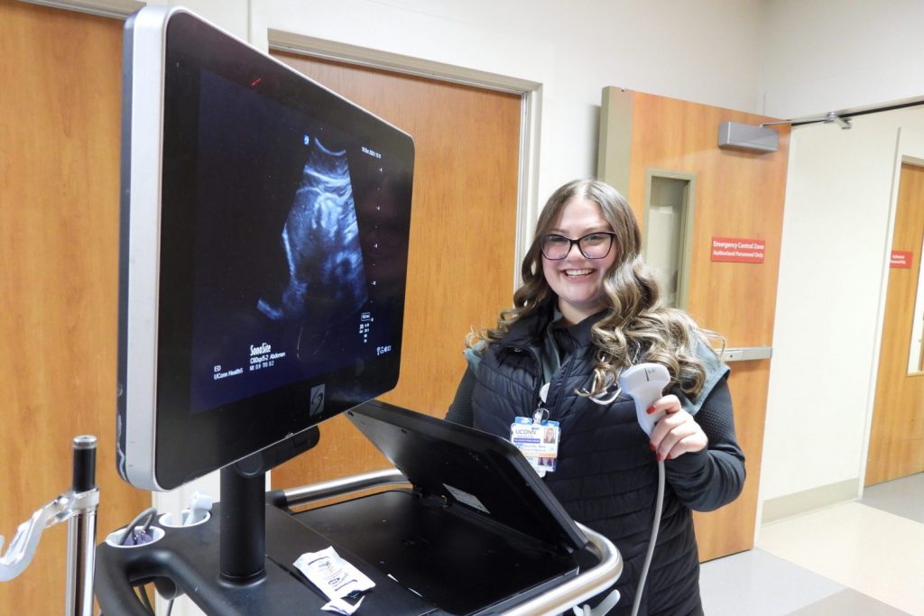 Niki Meka holding an ultrasdound in the ED smiling