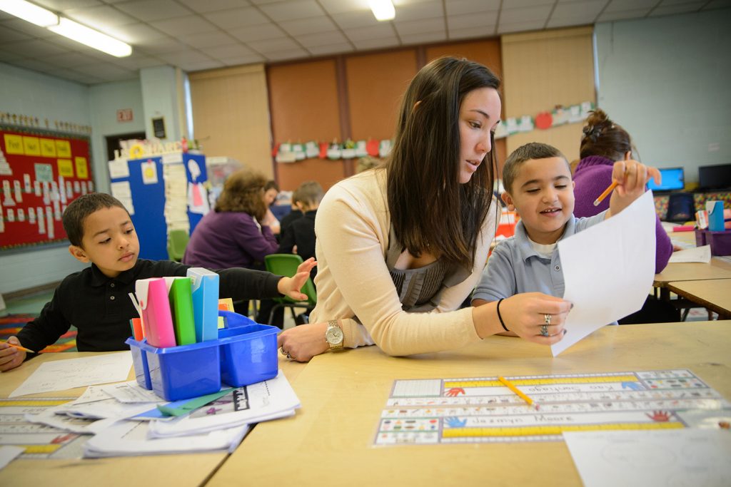 Female educator works with student on reading.
