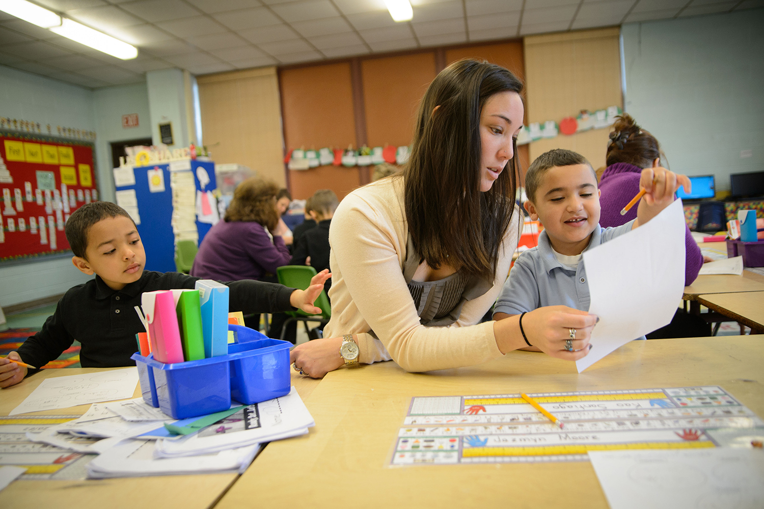 Female educator works with student on reading.
