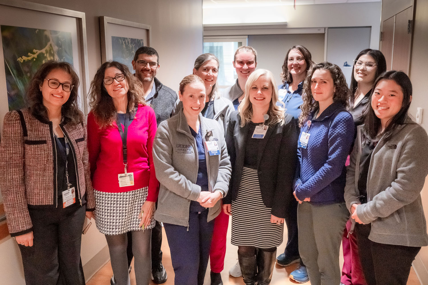 Group portrait of 11 in hospital floor hallway