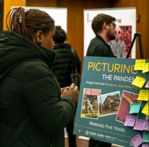 A person looking at a "Picturing the Pandemic" museum exhibit board