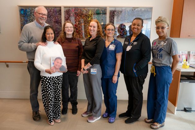 Group portrait of seven indoors in front of origami crane display
