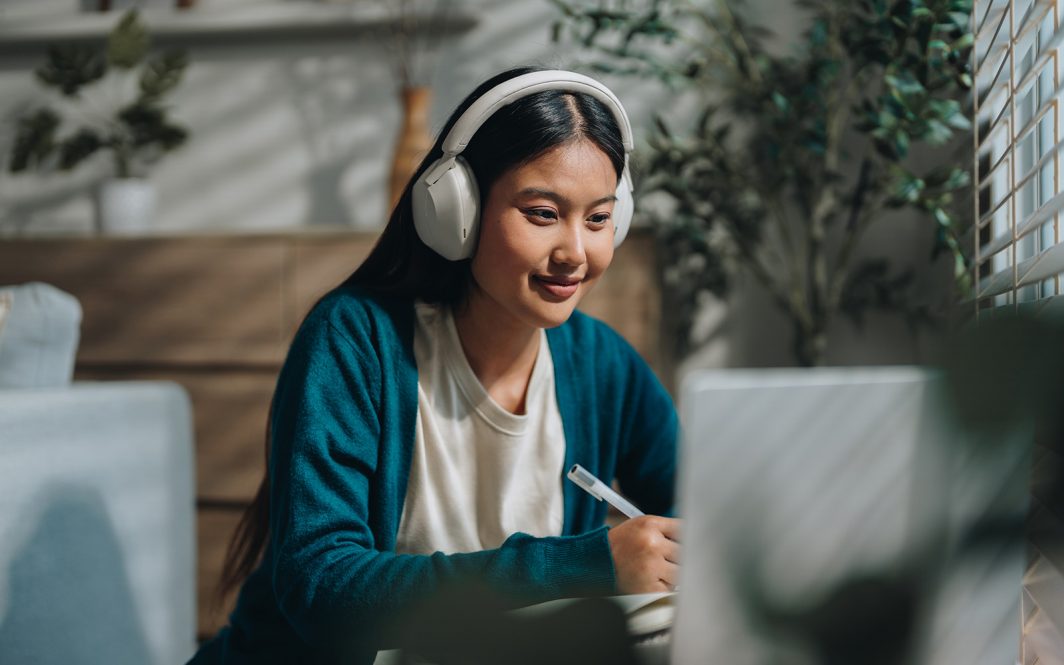 Woman enjoying her online class, attentively taking notes as she stays engaged and focused. With a sense of curiosity and dedication, she embraces the opportunity to learn from home and improve her knowledge