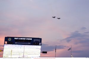 Planes flying in the sky over a Pratt & Whitney Stadium sign.