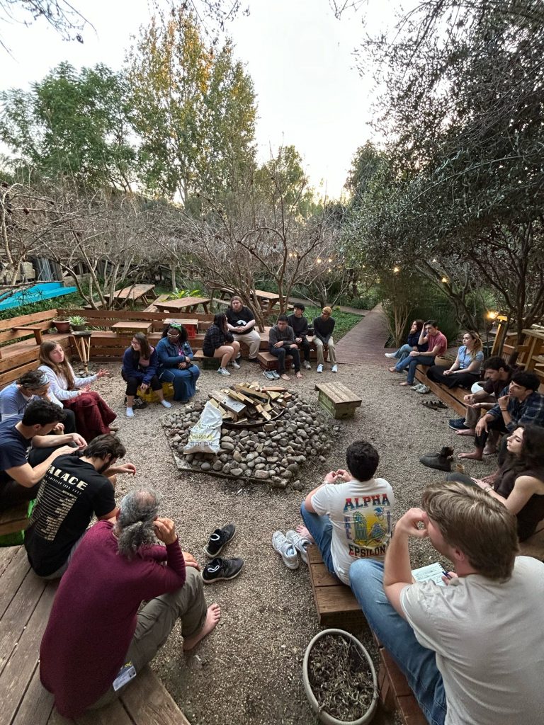 A group of people sit around a campfire.