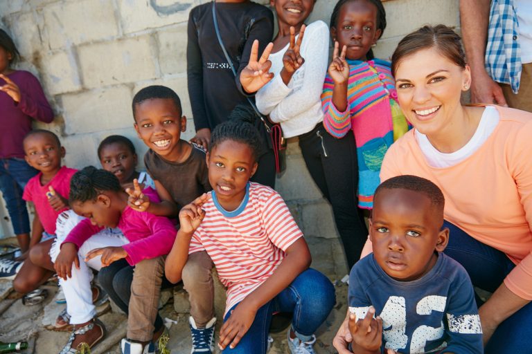 A female missionary poses with children outside
