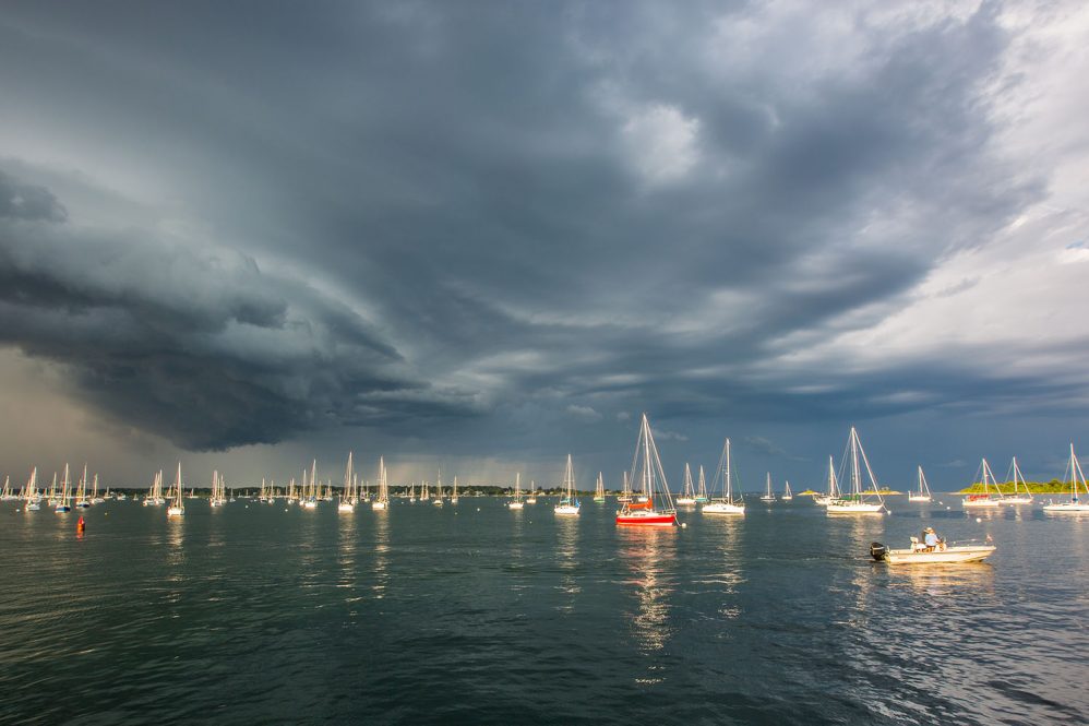 Ominous weather over a body of water with sail boats in the water