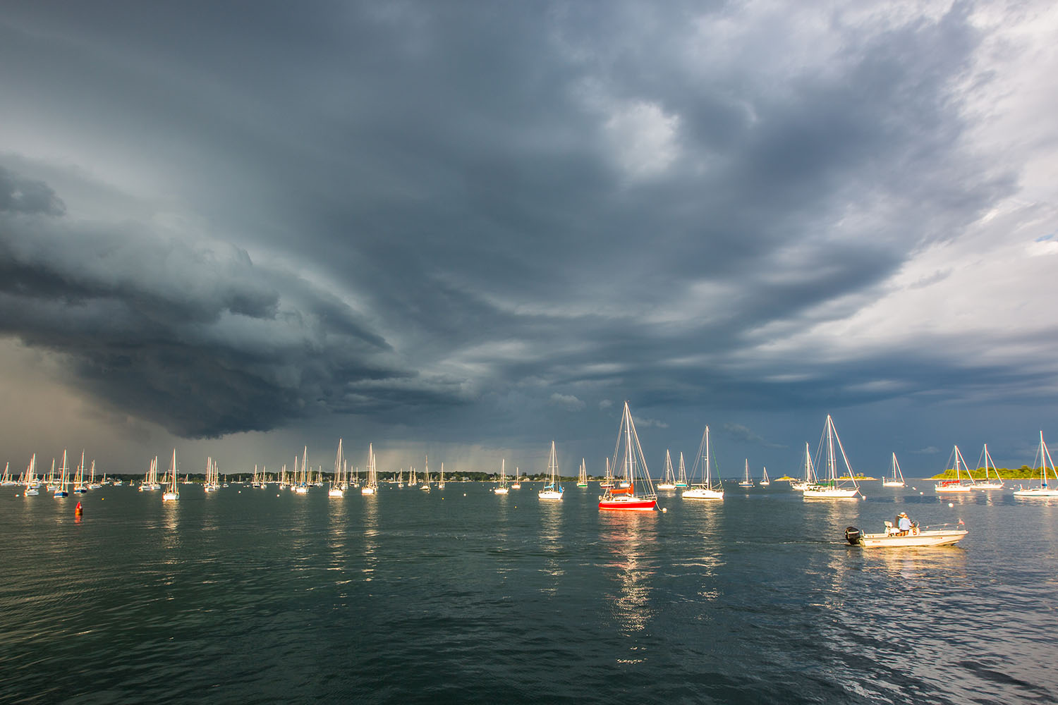 Ominous weather over a body of water with sail boats in the water