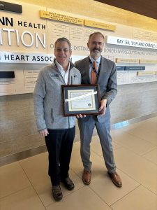 Two men stand together with a plaque
