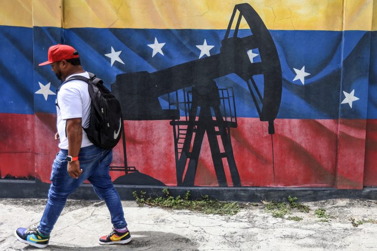 A man walks past a mural depicting an oil pumpjack on a Venezuelan flag in Caracas.