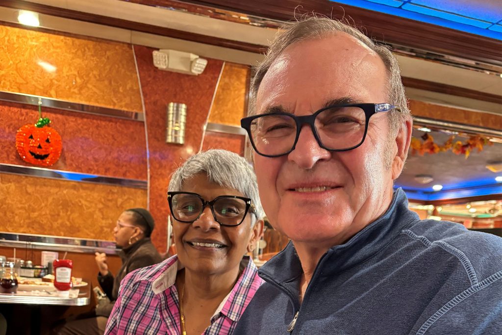 A man and a woman both with glasses pose for a photo in a restaurant