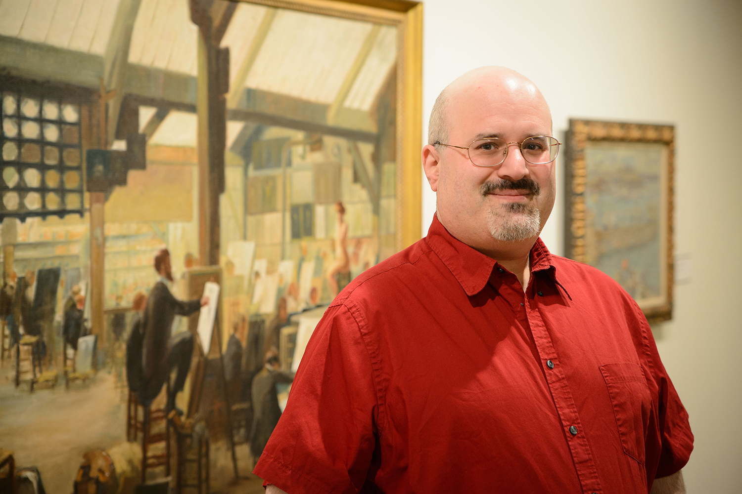 James Kaufman in a red shirt with a painting in the background.