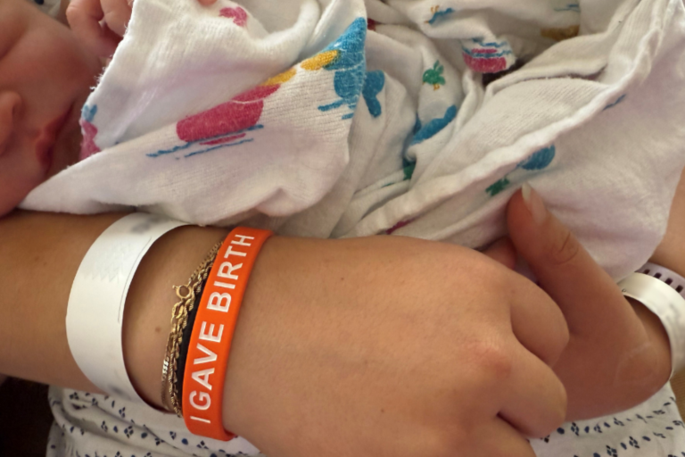 hand with an orange bracelet that says I gave birth