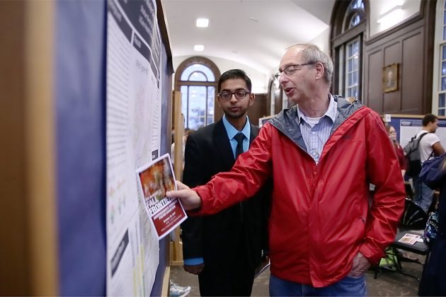 Moiseff gestures at a research poster while talking with a student.