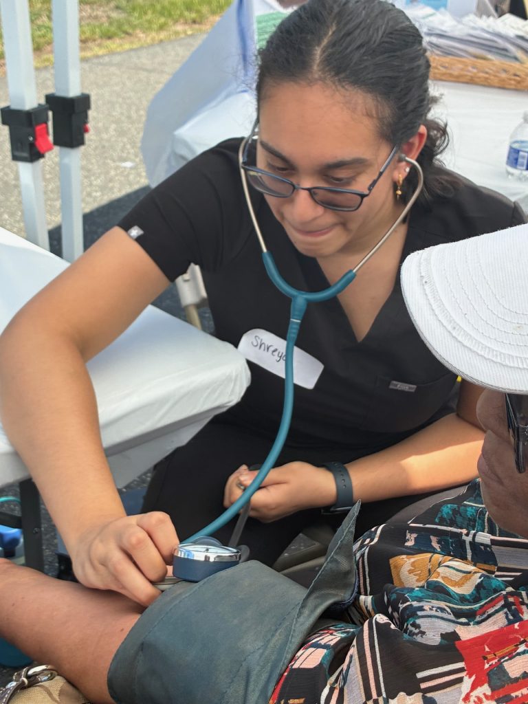 Student taking blood pressure of community member.