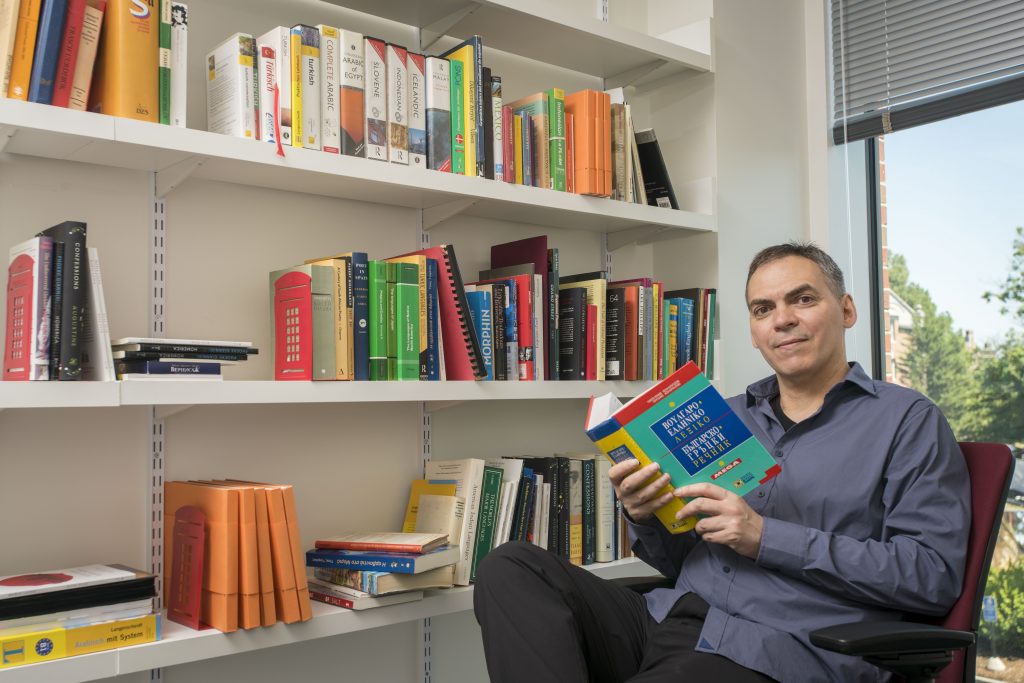 A man sitting reading a book surrounded by books