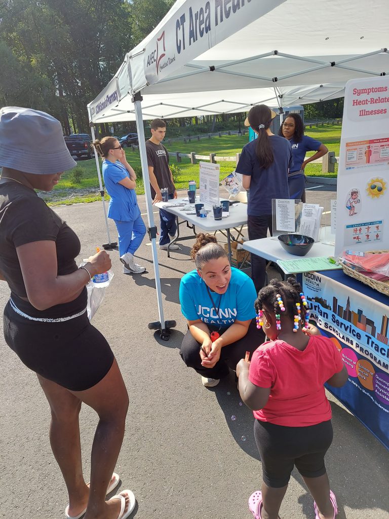Student community outreach at Keney Park in August 2025 with mother and child under tent (Photo by CT AHEC).
