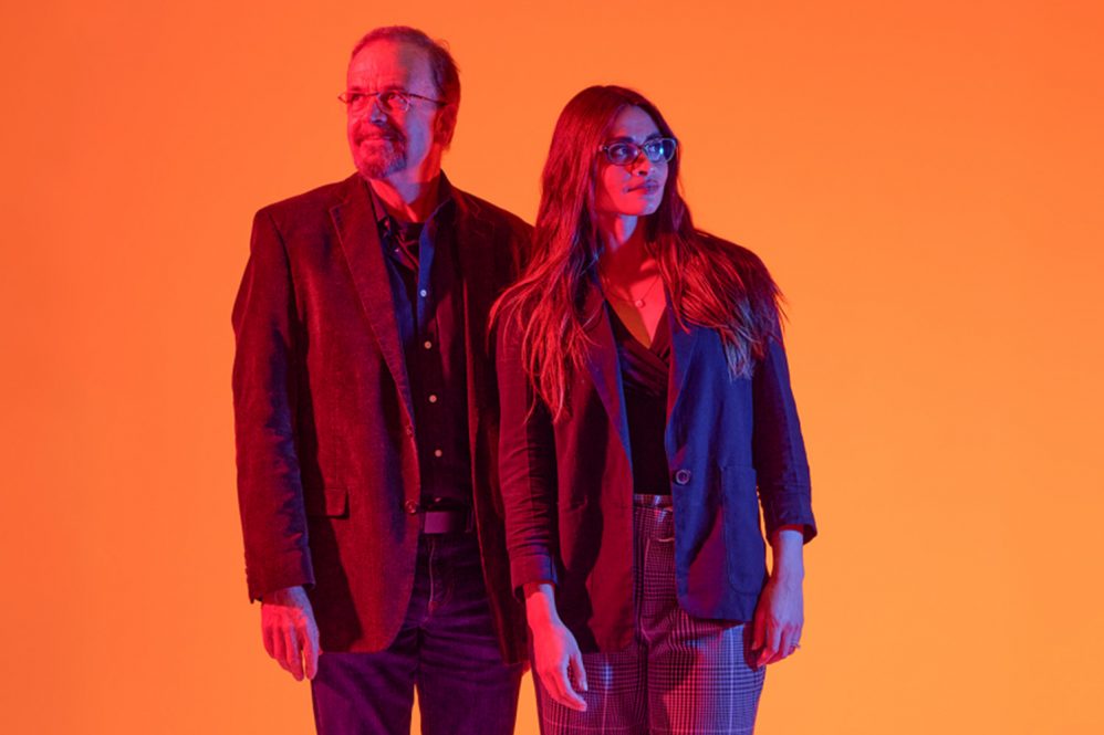 Jordan Ochs (FYE Program Director), and Bradley Wright (Professor of Sociology) stand tall against a gradient backdrop of orange and pink