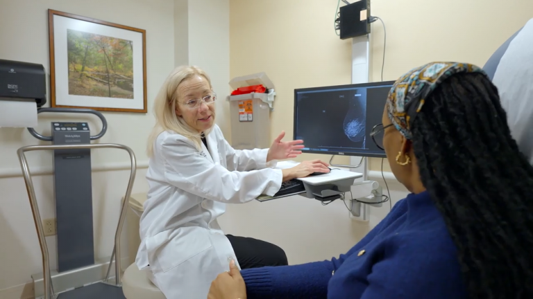 Dr. Sunny Mitchell, surgical oncologist, talks with a patient in an exam room at UConn Health.