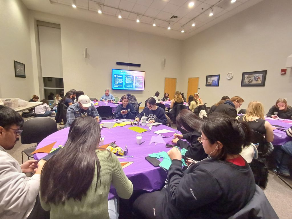 Students sitting at tables, making felt banners.