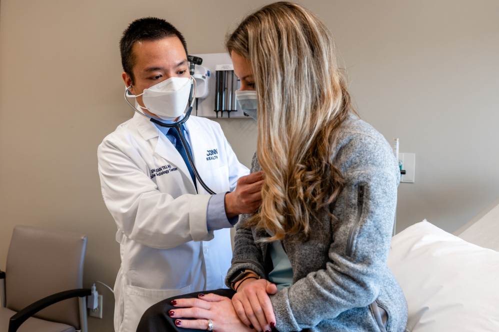 A doctor is using a stethascope to check a women's heart
