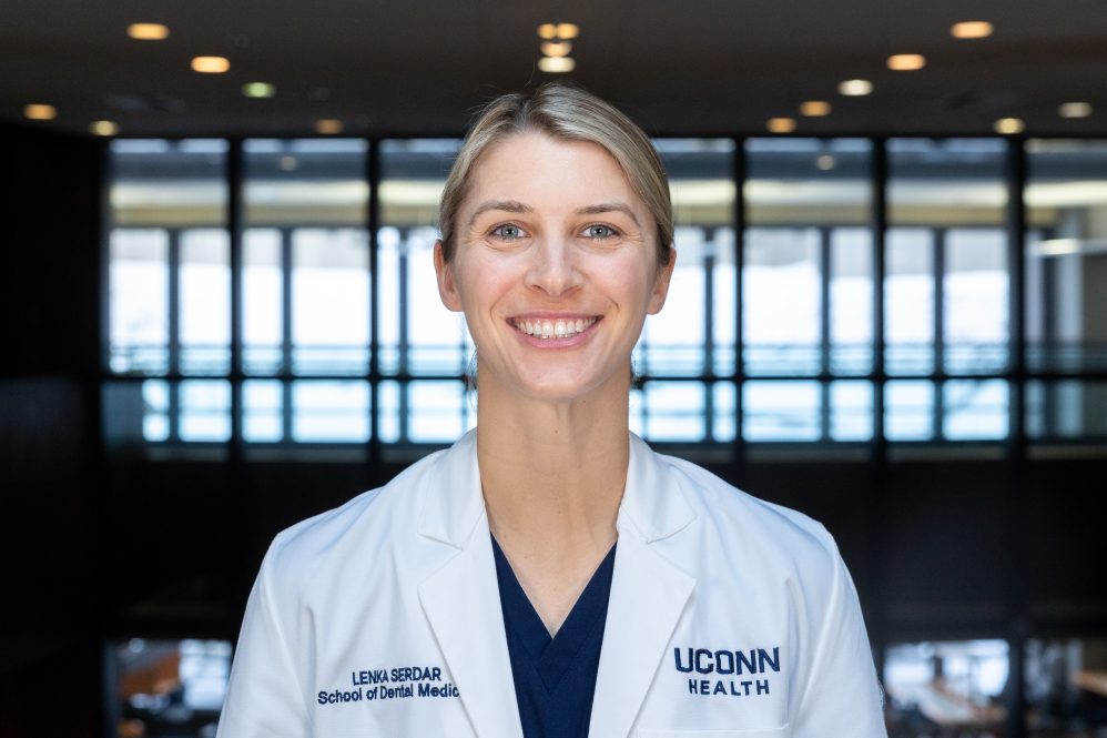 A woman in a white coat poses for a photo
