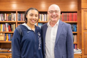 A man and a woman pose in front of a bookshelf for a photo
